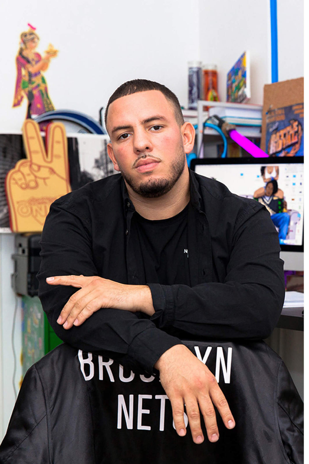 male model posing with a brooklyn nets black bomber jacket draped on a chair