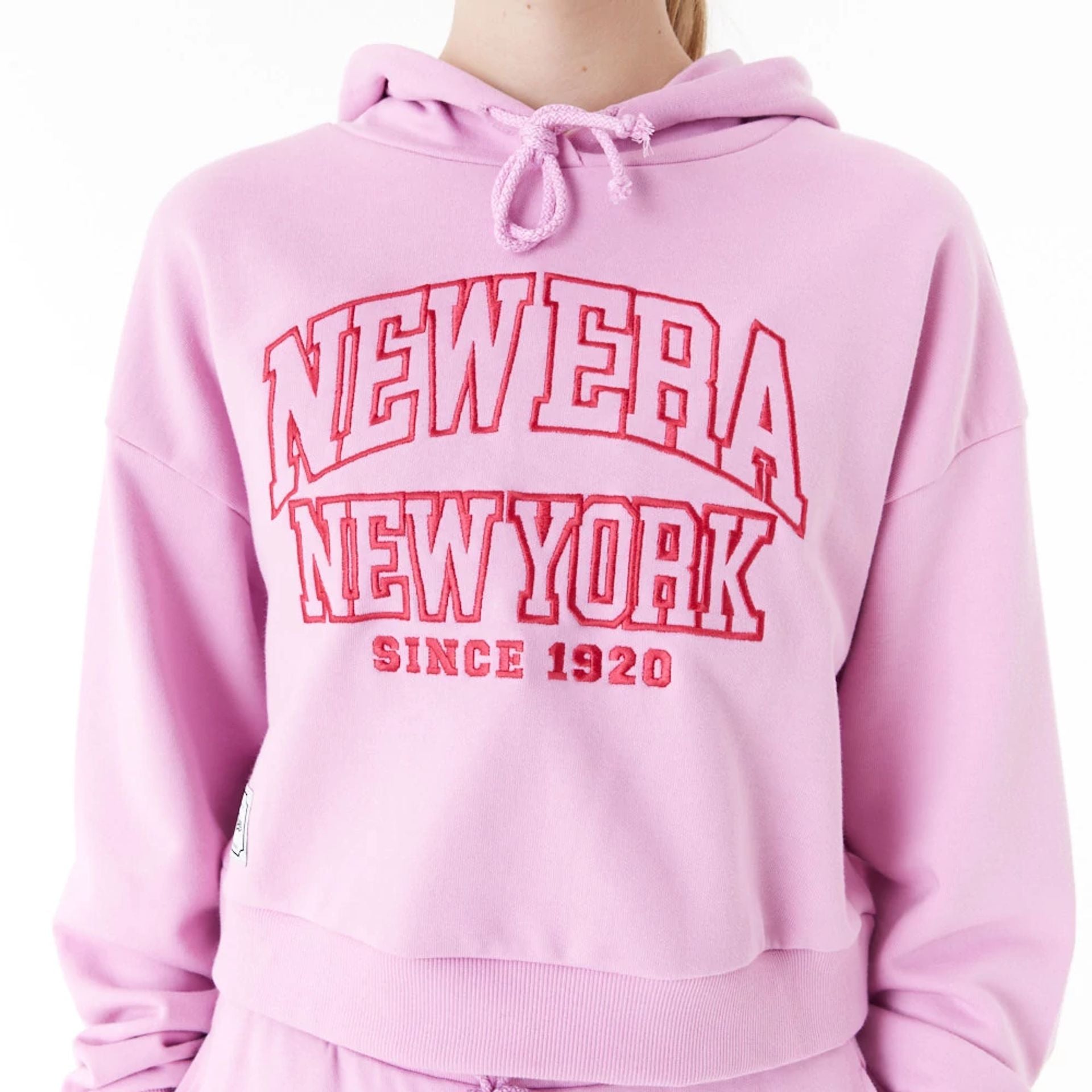 The Female model is wearing New Era Womens Arch Wordmark Pink Crop Pullover Hoodie 8