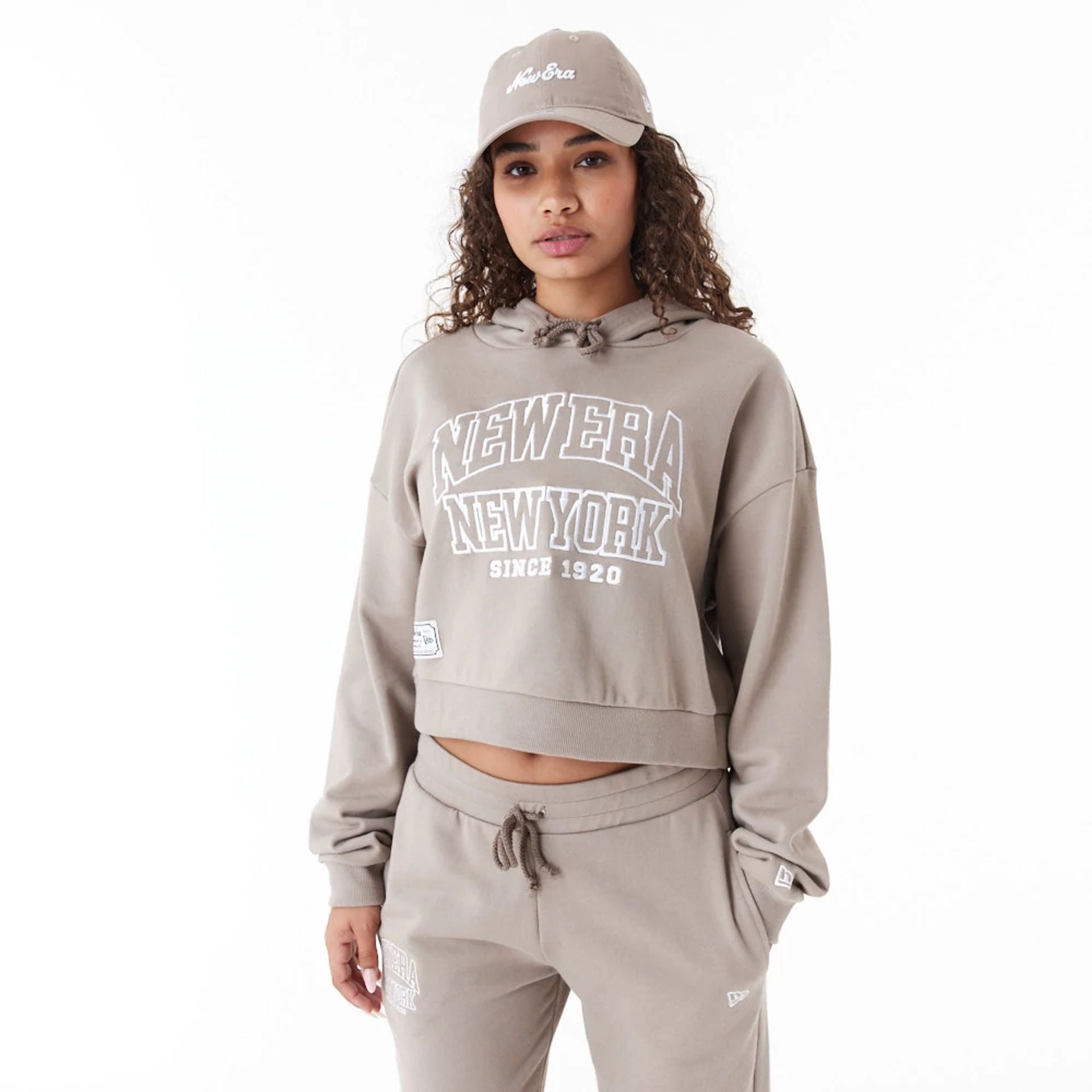 The Female model is wearing New Era Womens Arch Wordmark Brown Crop Pullover Hoodie 1