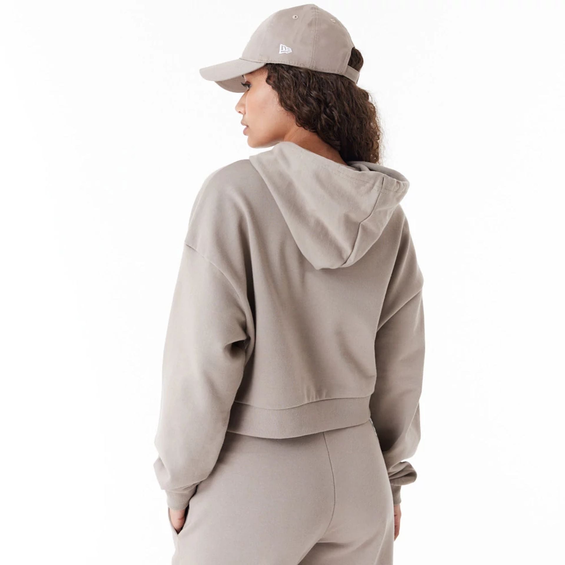 The Female model is wearing New Era Womens Arch Wordmark Brown Crop Pullover Hoodie 6