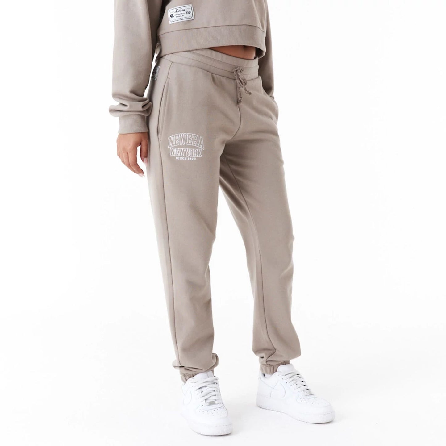 The Female model is wearing New Era Womens Arch Wordmark Brown Joggers 1