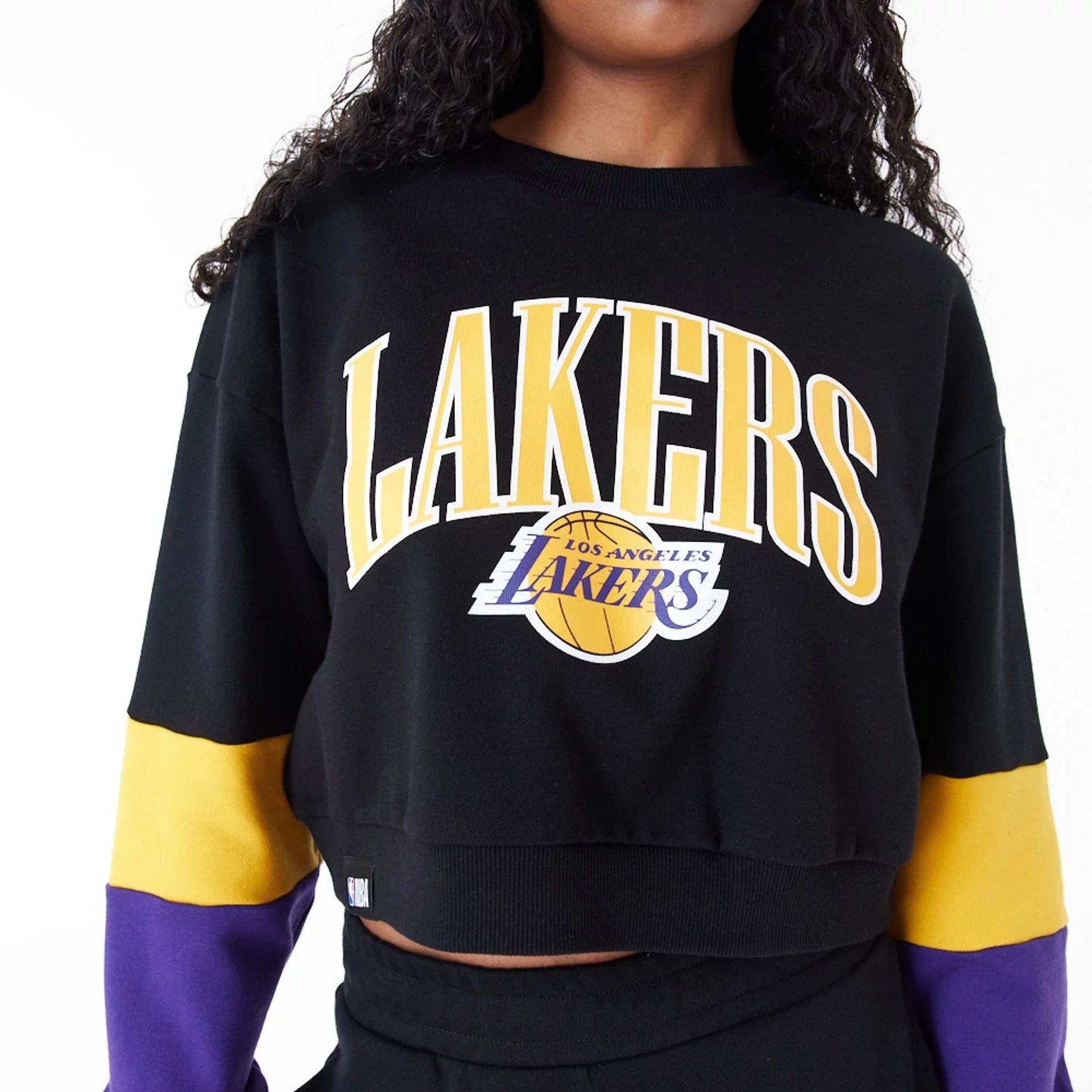 The Female model is wearing LA Lakers Womens NBA Colour Block Black Crop Crew Neck Sweatshirt 2