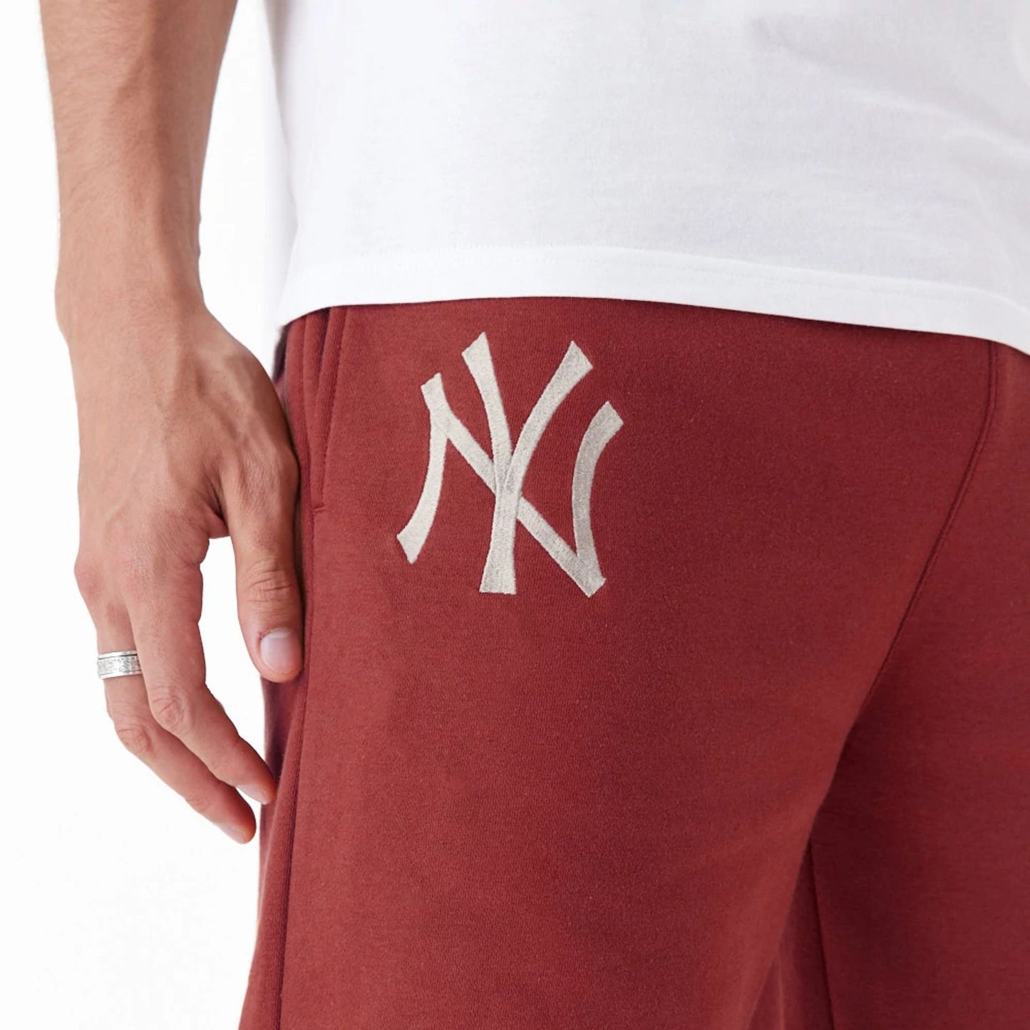 The Male model is wearing New York Yankees League Essential Copper Fleece Joggers 3