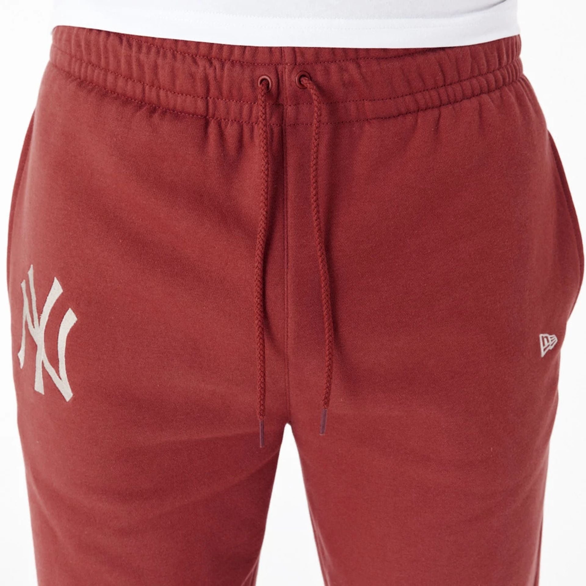 The Male model is wearing New York Yankees League Essential Copper Fleece Joggers 5