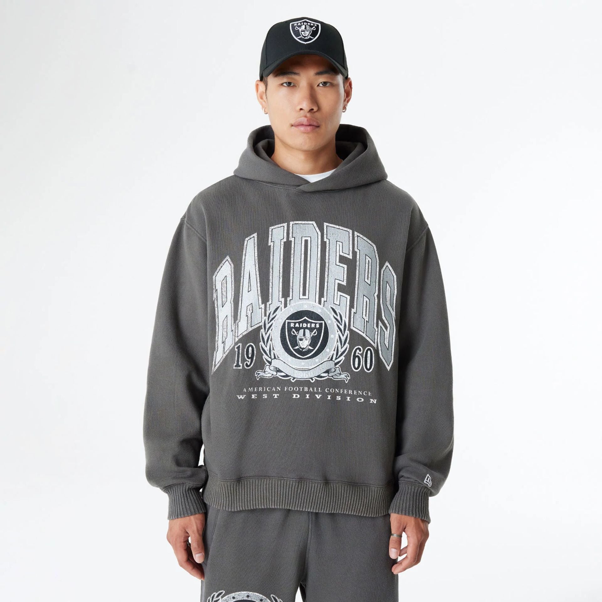 The Male model is wearing Las Vegas Raiders Oversized Essential Dark Grey Oversized Pullover Hoodie 1