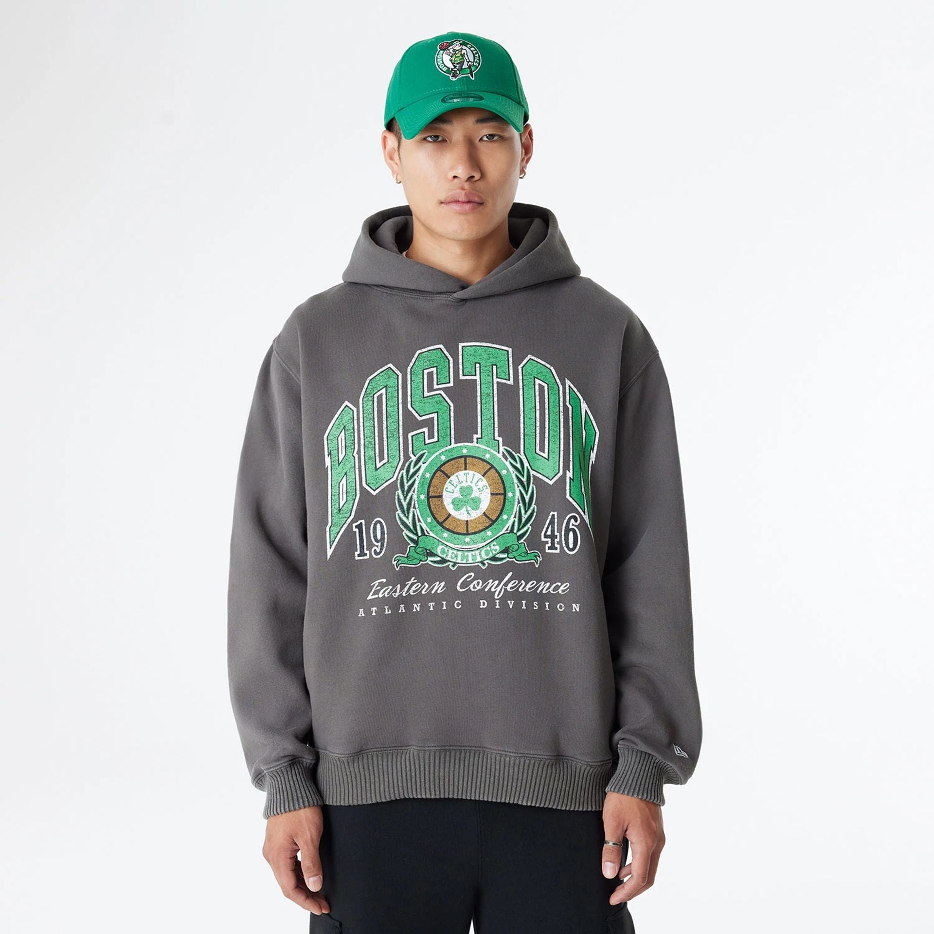 The Male model is wearing Boston Celtics Oversized Essential Dark Grey Oversized Pullover Hoodie 1