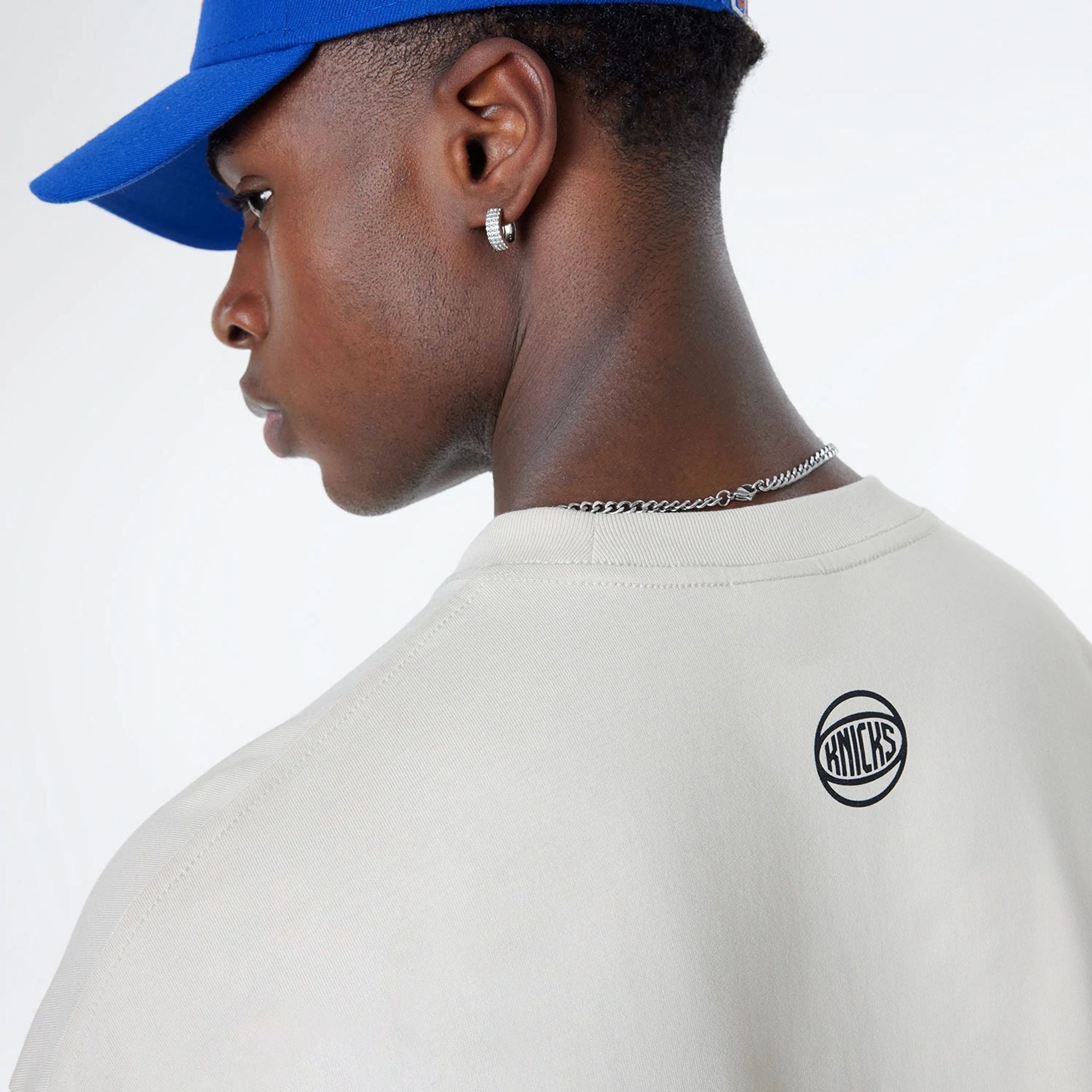 The Male model is wearing New York Knicks Bristol Studio x NBA Light Beige Oversized T-Shirt 7