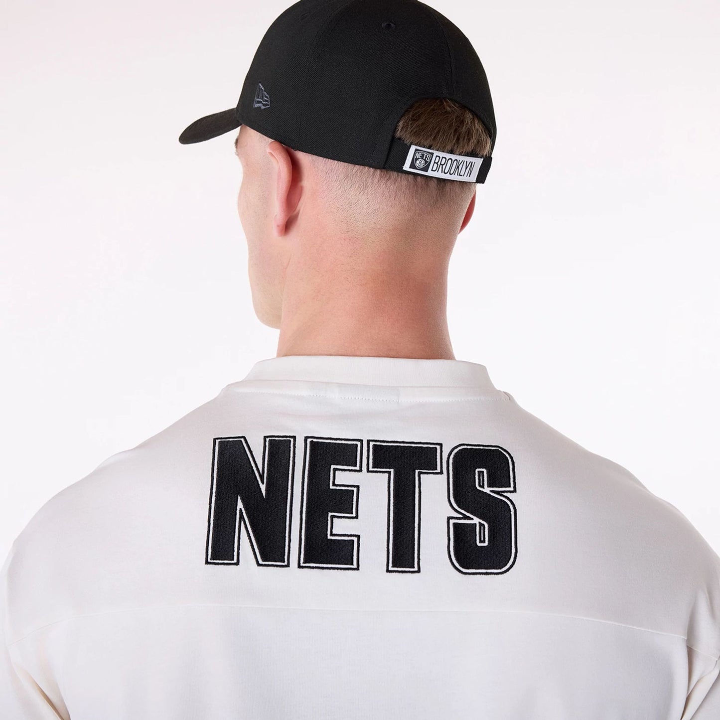 The Male model is wearing Brooklyn Nets NBA Wordmark Open White Oversized T-Shirt 6