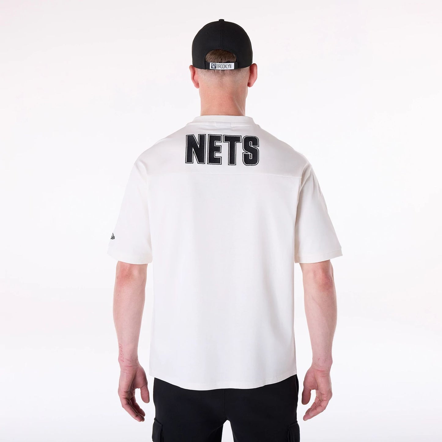 The Male model is wearing Brooklyn Nets NBA Wordmark Open White Oversized T-Shirt 2