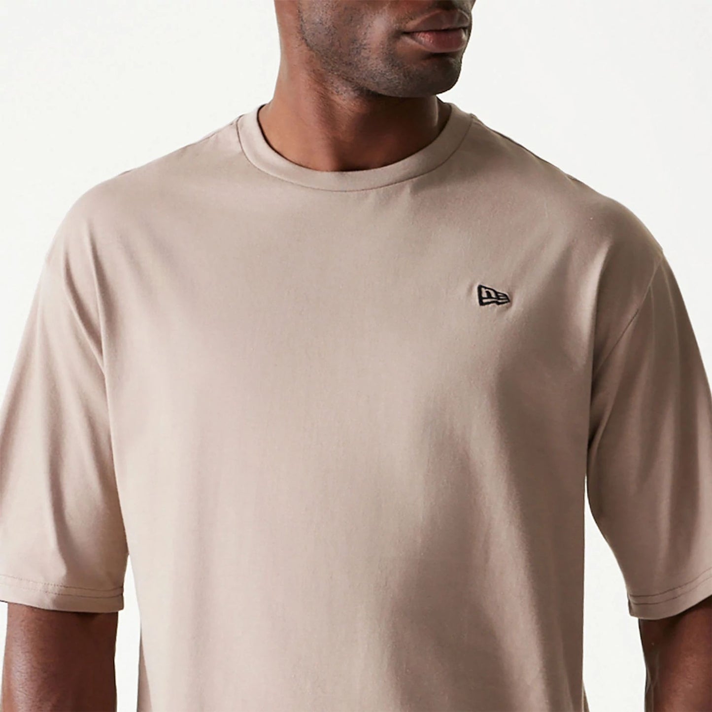 The Male model is wearing New Era Essential Pastel Brown Oversized T-Shirt 3