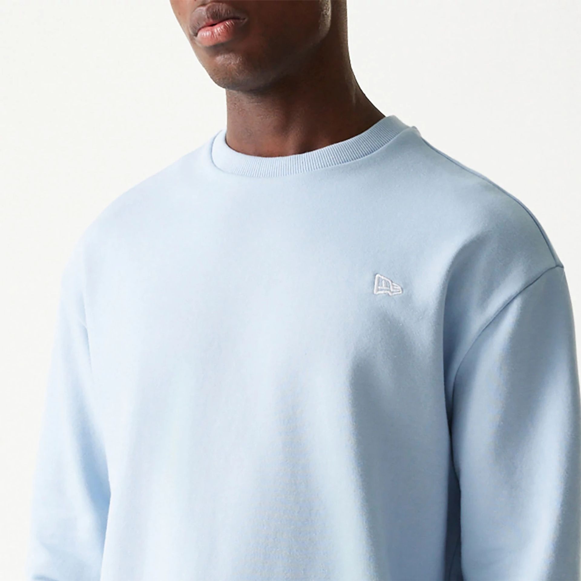 The Male model is wearing New Era Essential Pastel Blue Crewneck Sweater 3