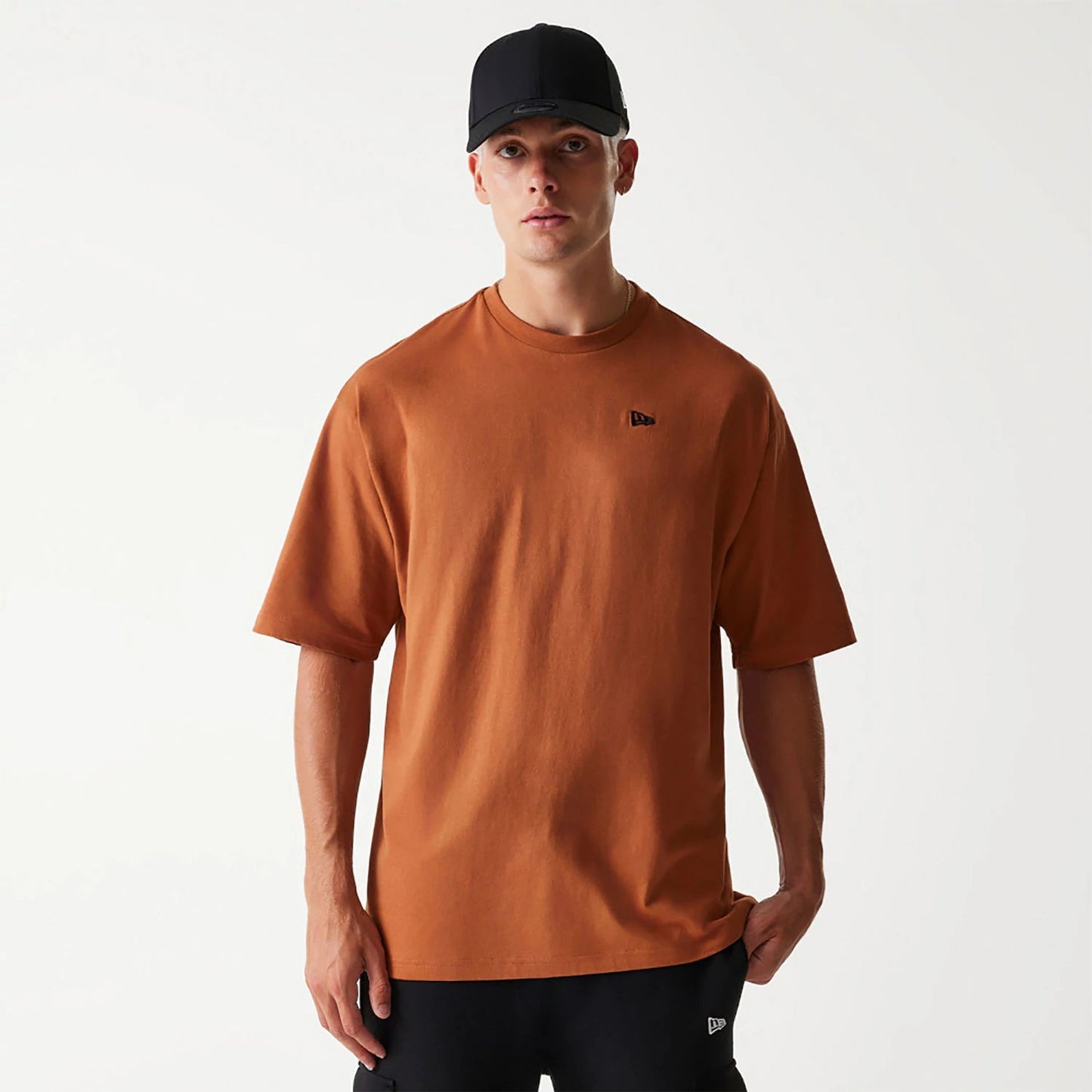 The Male model is wearing New Era Essential Brown Oversized T-Shirt 1