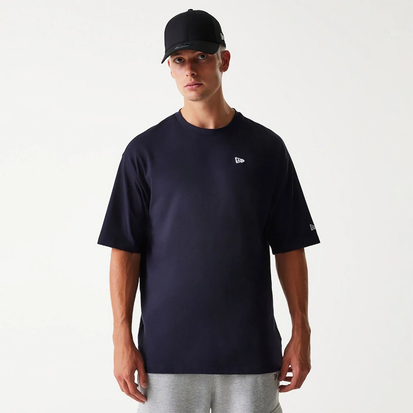 The Male model is wearing New Era Essential Navy Oversized T-Shirt 1