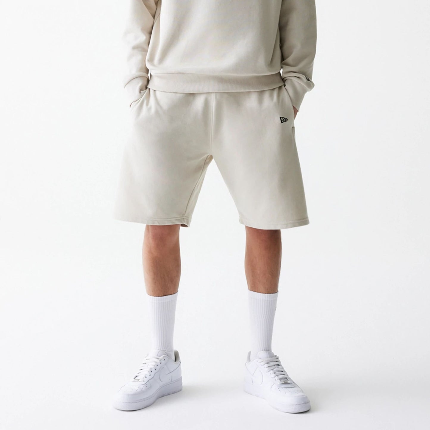 The Male model is wearing New Era Cream Oversized One Panel Shorts 1