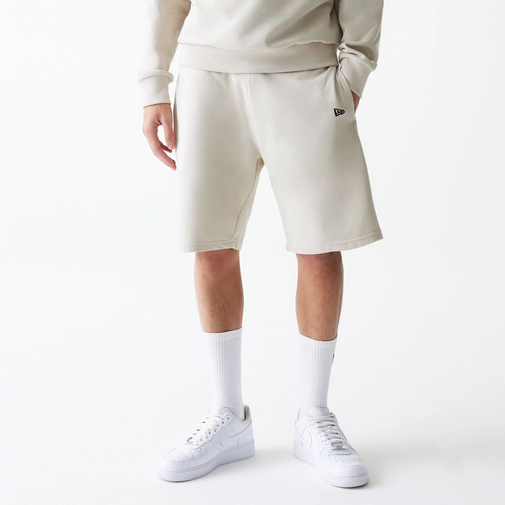 The Male model is wearing New Era Cream Oversized One Panel Shorts 6