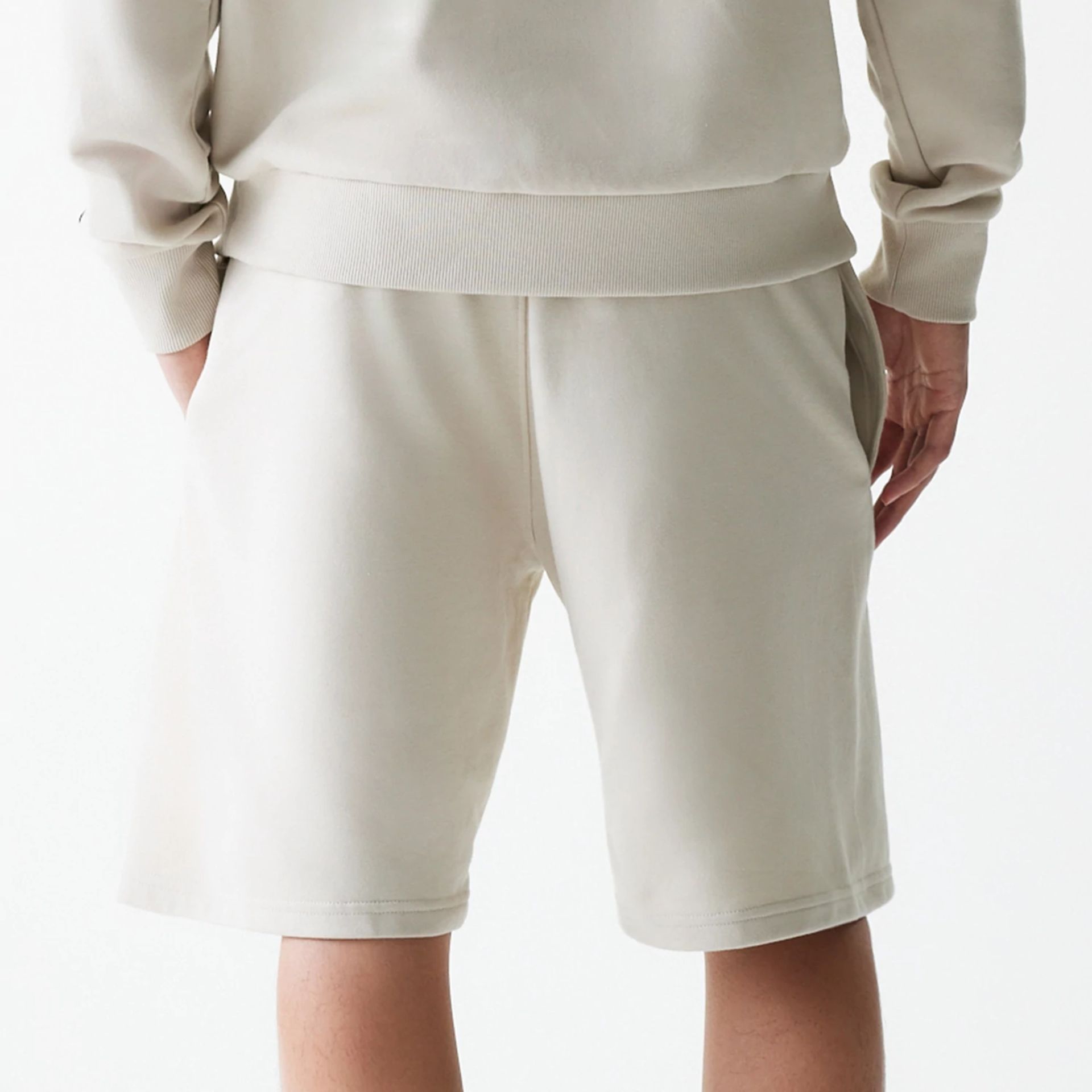 The Male model is wearing New Era Cream Oversized One Panel Shorts 7