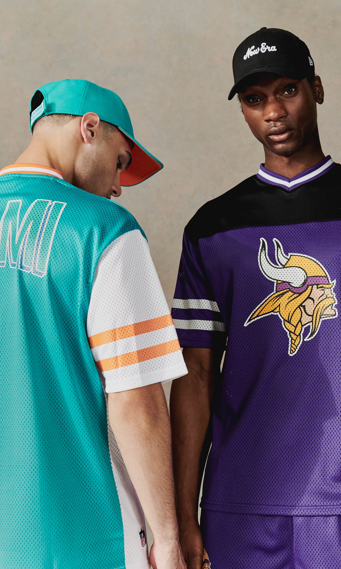 two men wearing NFL sports jerseys with caps 