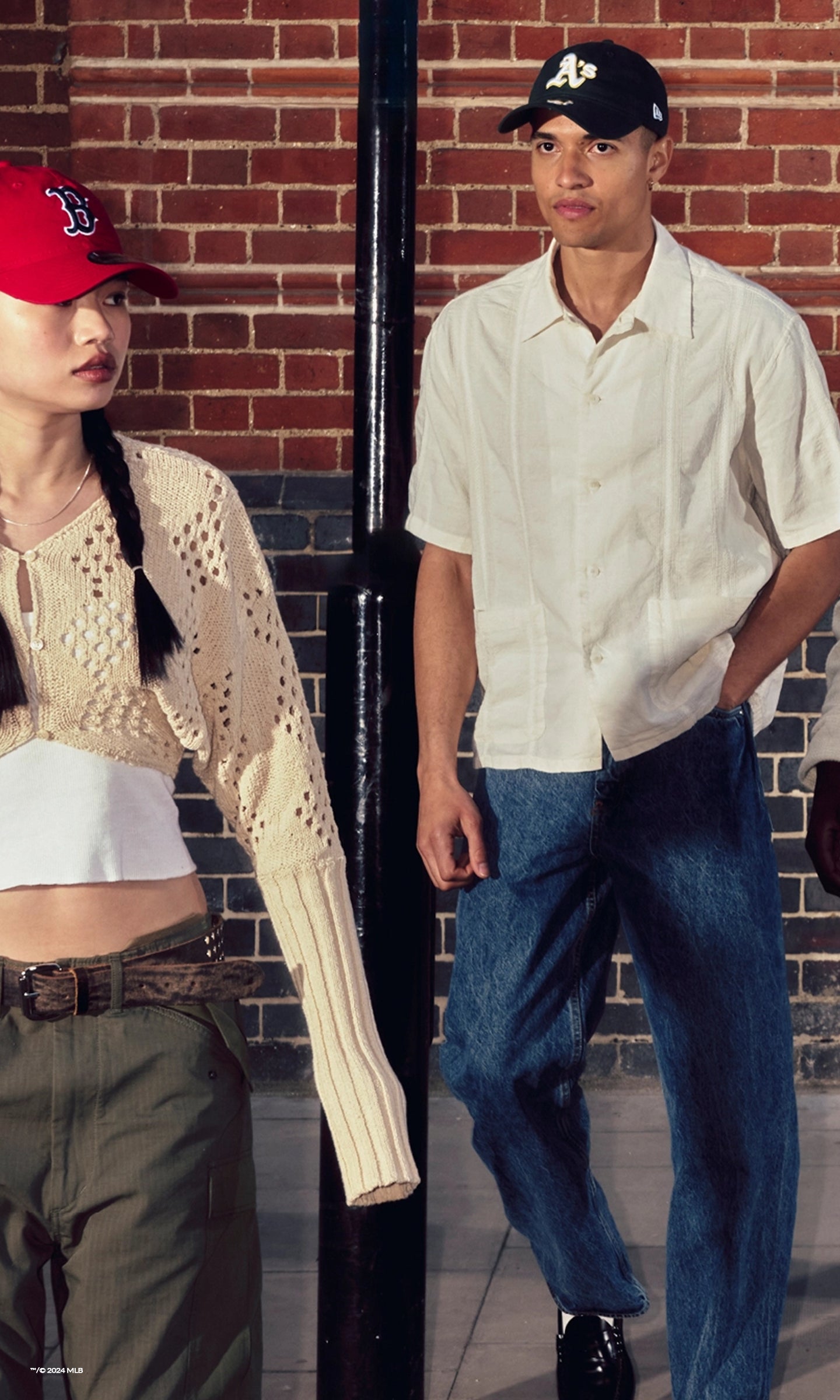 a girl and boy wearing walking in the street wearing new era headwear 