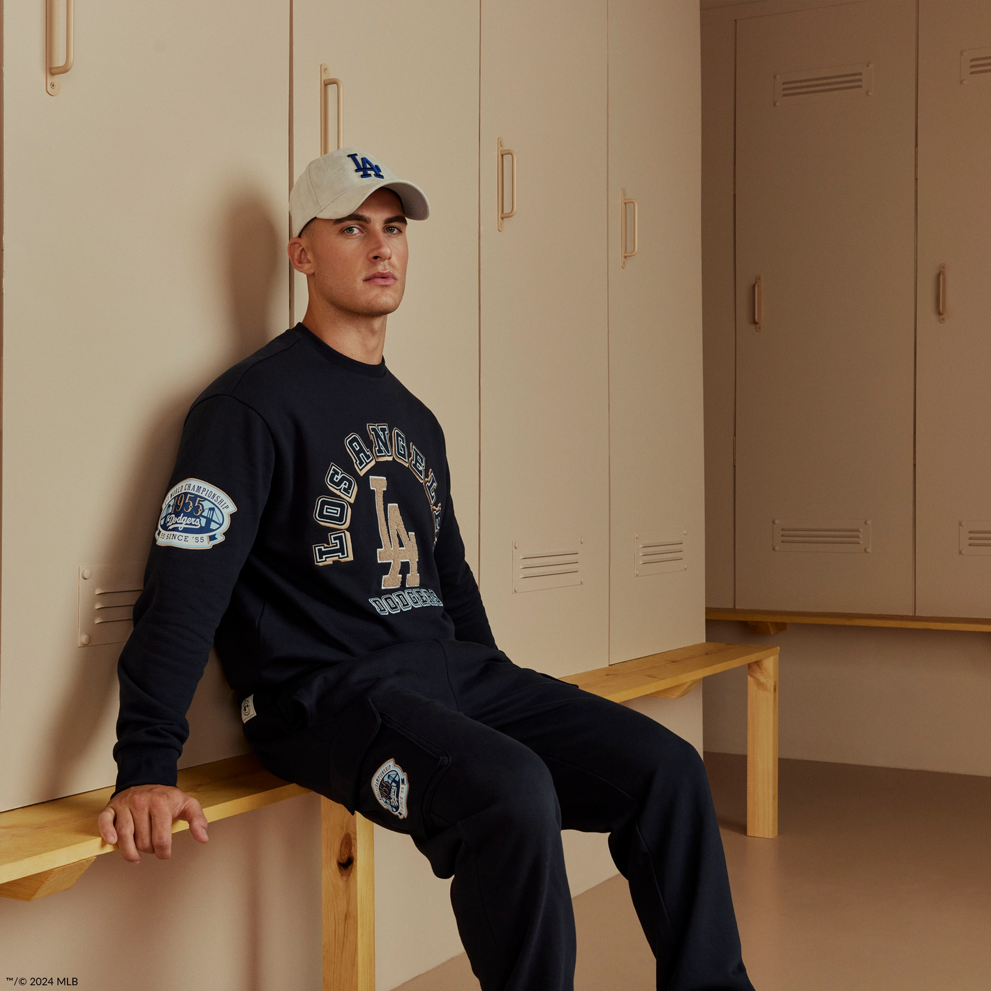 male model wearing a navy Los angeles dodgers matching sweatshirt, joggers and cap