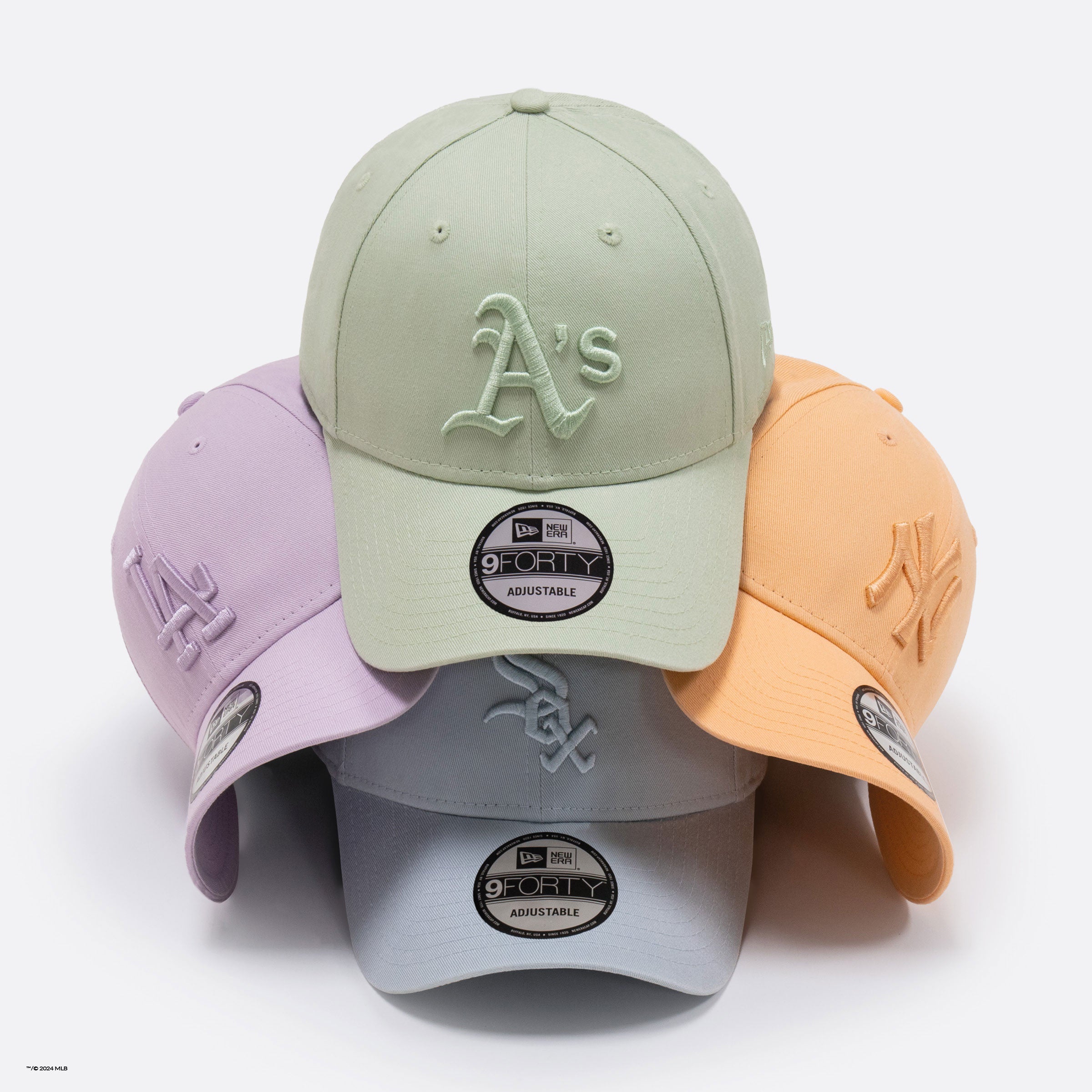 four pastel washed mlb caps stacked on top of each other 