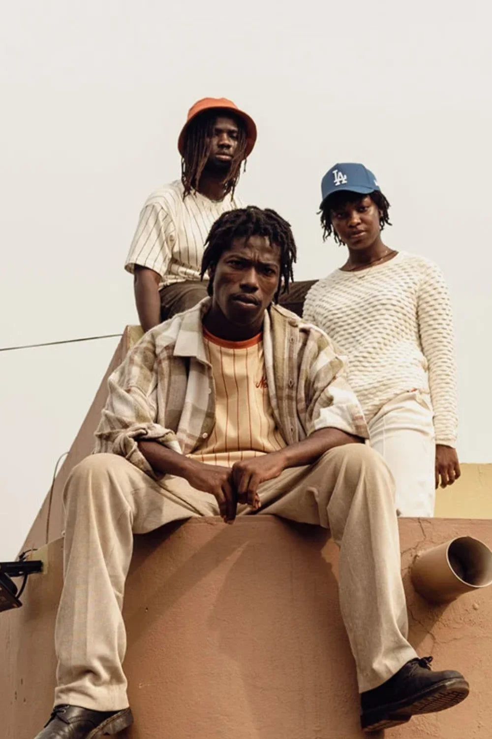 young adults posing for accra's new wave wearing new era caps and tees