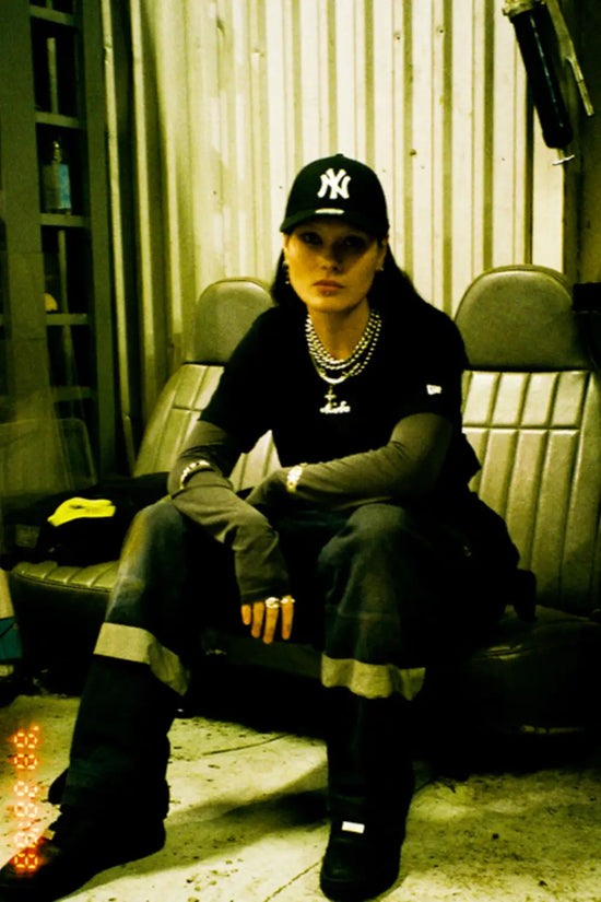 Slide 2:A woman wearing a black New York Yankees cap for the New Era x Icelandic Rap collaboration.