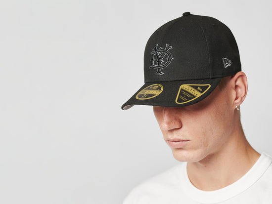 Slide 6:Man wearing a black Live Fast Die Young curved visor cap.