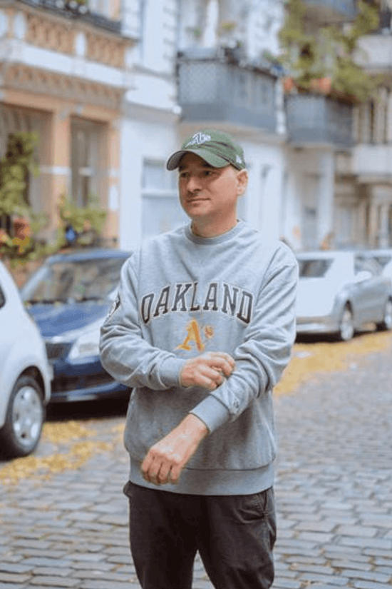 Slide 1:man wearing a grey sweatshirt and green cap with the oakland athletics logo 