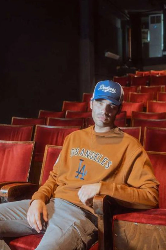 Slide 3:man wearing an orange la dodgers sweatshirt and blue cap