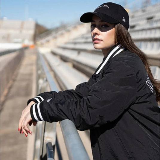 marta garcia wearing a new era black bomber jacket and cap