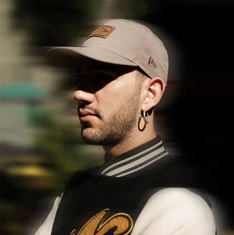man wearing a new era branded beige cap and black and white varsity jacket